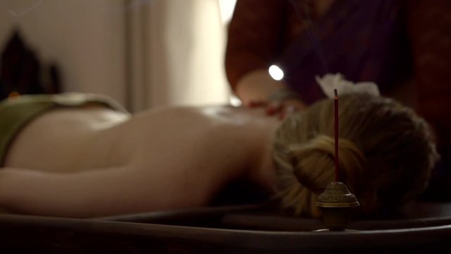 master of massage is massaging back of woman lying on couch, medium shot