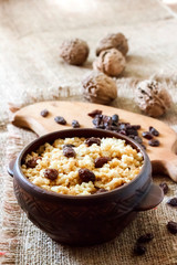 Sweet millet porridge with dark raisins in ceramic rustic bowl