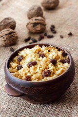 Sweet millet porridge with dark raisins in ceramic rustic bowl