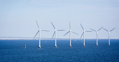Offshore wind farm in the Baltic Sea off the coast of Copenhagen, Denmark with the Oresund Bridge...