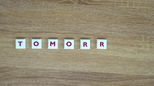 Word "Tomorrow" is made up of letters on a wooden background. Design for presentation of business idea, startup, report. Word "Tomorrow" is written from letters on table. Video saver.