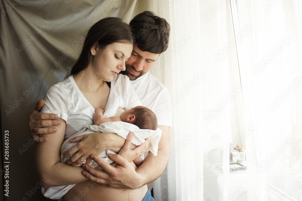 Wall mural father and mother with a newborn son. new young multi-generation family. breast-feeding