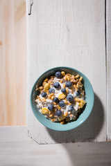 Obraz na płótnie Canvas Healthy breakfast table concept. Plate with oatmeal cereal flakes and blueberries on a light wooden surface