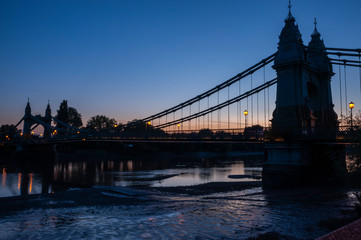 A silhouette of the Hammersmith Bridge in London at dusk.