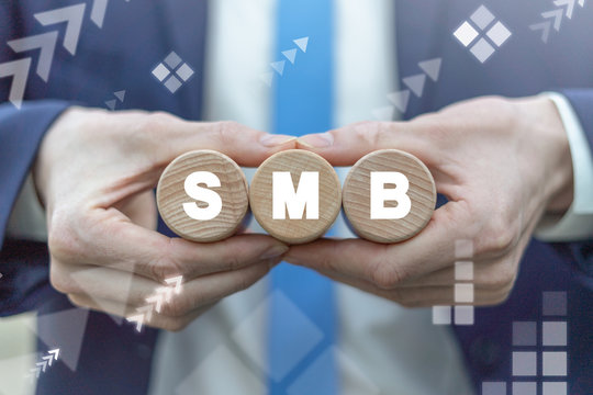 SMB Small Medium-sized Business concept. SMB acronym on wooden kegs in businessman's hands.