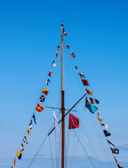 Mast with signal flags against blue sky.