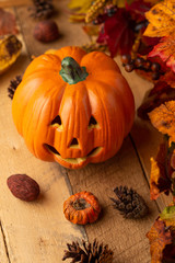 Halloween pumpkin with leaves and pine cones and elements of decor on an old wooden table. View from above. vertical frame. autumn mood