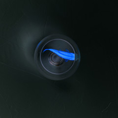 A small blue fish swims in a glass of water with water. Lonely fish. Dark background, texture. Pop art design, creative concept.