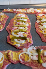 preparing beef rouladen, fresh raw meat coated with mustard and onions