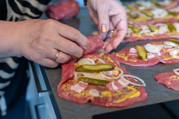 preparing beef rouladen, fresh raw meat coated with mustard and onions