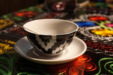 cup of tea with black and white ornament on hand-made tablecloth with flowers