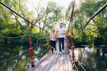 Couple guy and girl running on the bridge over the river