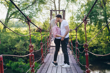 Young couple guy and girl on the bridge over the river and kiss