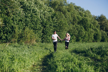 Fototapeta na wymiar Couple guy and girl running hand in hand on the road in nature