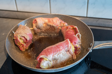 beef roulades, german stuffed meat rolls roast in a pan on the black stove
