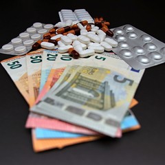 Pills and capsules with money on red background.