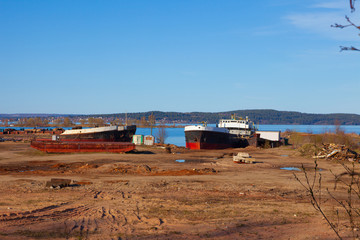 Old, abandoned ships in the port on a background of blue lake