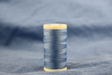 sewing thread. blue color. on blue fabric. blue fabric background