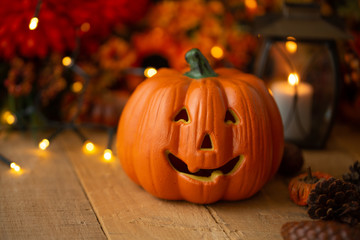 Halloween pumpkin with leaves on an old wooden table with luminous lights and an old lamp. Autumn mood and atmospheric photo