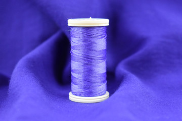 sewing thread. purple color. on purple fabric. purple fabric background