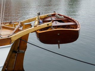 Dinghy, small rowing boat made of mahogany wood, attached to the stern of a sailing yacht