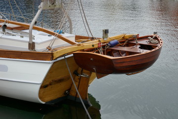 Dinghy, small rowing boat made of mahogany wood, attached to the stern of a sailing yacht