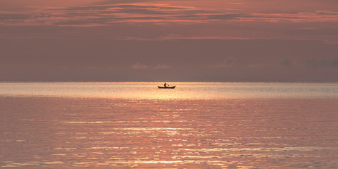 Fishermen boat silhouette against orange sunrise on Lake Malawi, the sun glitter on the Lake, South-East-Africa