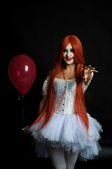 girl with red hair in clown costume on black background