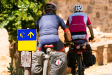 way of st james to Santiago de  Compostela , cyclists on the road with shell and yellow arrow signals - obrazy, fototapety, plakaty