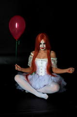 girl with red hair in clown costume on black background