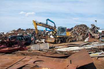 crane holding rusty metal in recycling junkyard