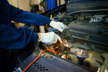 worker repairs car engine with shallow depth of field