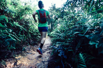 Woman ultra marathon runner running on tropical forest trail