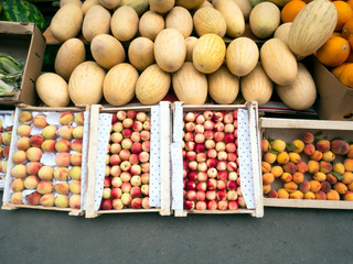 Ripe garden peaches, nectarine and melons in the wooden boxes. Selling fruits in the market.