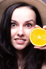 young woman with a hat on her head is holding an orange