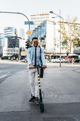 Young modern man using and driving electric scooter on city street. Modern and ecological transportation concept.