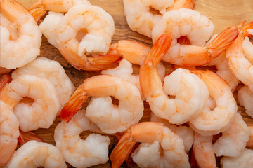 Background of shrimp, macro. Sea food, wholesome and tasty food. On a wooden background. Background for cooking, menu, selling seafood