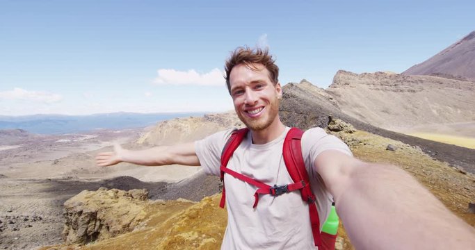Selfie Video - Smiling young man backpacker taking video selfportrait in beautiful mountains. Healthy hiking man enjoying at Tongariro Alpine Crossing landscape, Tongariro National Park, New Zealand