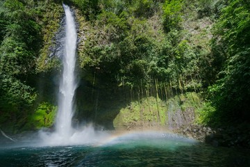 Fototapeta na wymiar La fortuna waterfall creating a rainbow in it´s base on a sunny day, Alajuela, Costa Rica.