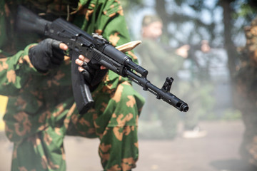 A guy with a gun in his hands. A man in uniform with a firearm. The barrel of a machine gun for shooting. A guy in the army serves his military command.