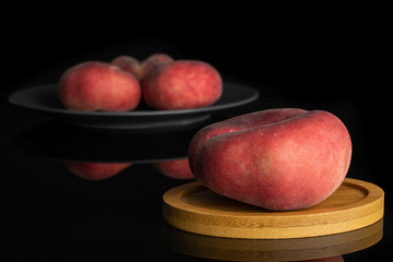 Group of four whole fresh red peach prunus persica platycarpa on gray ceramic plate on round bamboo...