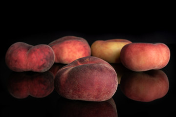 Group of five whole fresh red peach prunus persica platycarpa isolated on black glass
