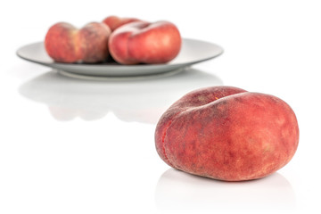 Group of four whole fresh red peach prunus persica platycarpa on gray ceramic plate isolated on white background
