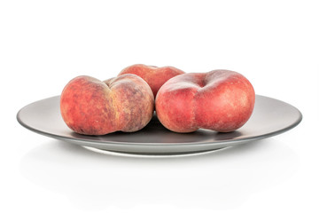 Group of three whole fresh red peach prunus persica platycarpa on gray ceramic plate isolated on white background