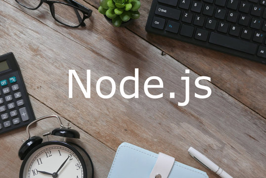Top view of keyboard,plant,sunglasses,pen,notebook,clock and calculator on wooden background written with Node.js.