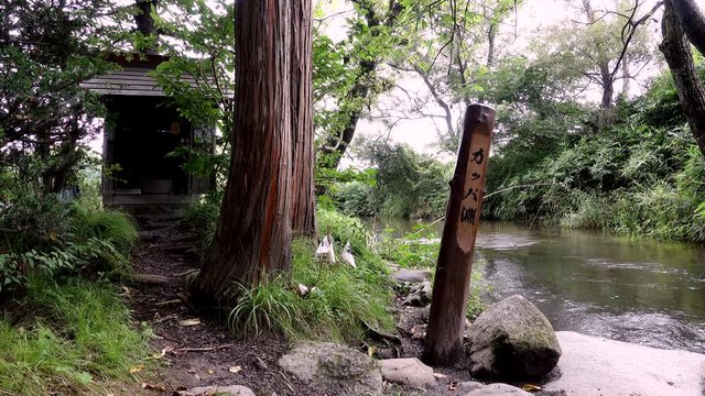 Sign and shrine on riverbank, Tono, Iwate Prefecture, Japan