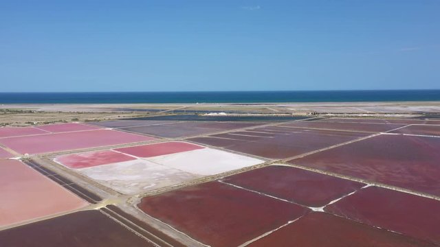 Aerial view over pink salt marshes and mediterranean sea in background salin de la Palme Aude Occitanie