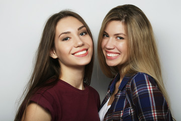 lifestyle and people concept: Two young girl friends standing together and having fun. Looking at camera.