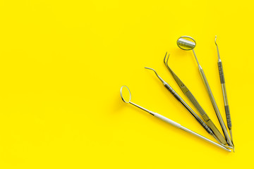 Dentist tools for cure teeth on yellow background top view copy space