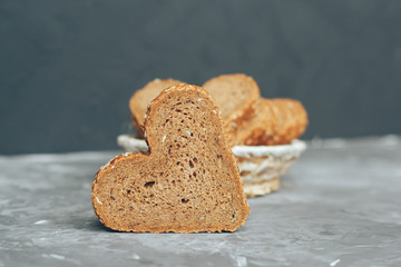 Rye bread in the shape of heart cut into slices on a gray background